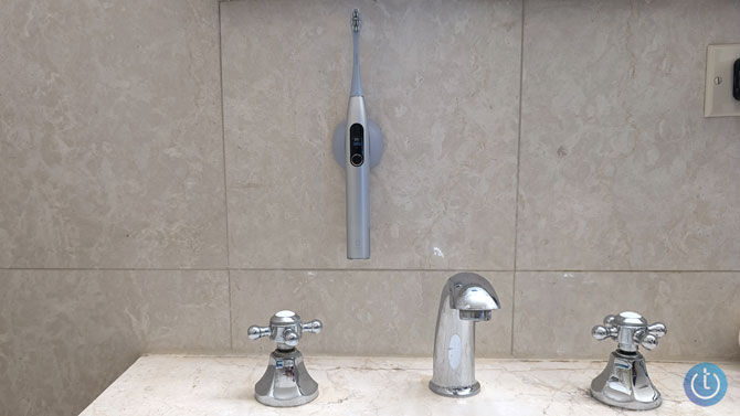 The Oclean X Pro Digital toothbrush is shown mounted on the wall in its magnetic holder.